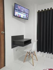 a room with a chair and a television on a wall at Hotel Chemy in Quito