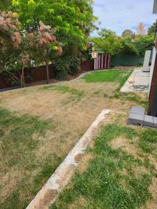 a yard with grass and a fence and trees at Treasure in Karabah in Queanbeyan