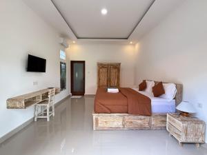 a bedroom with a bed and a desk in it at Puri Lepang Riverside in Ketewel