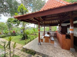 a patio of a house with a table and benches at Puri Lepang Riverside in Ketewel