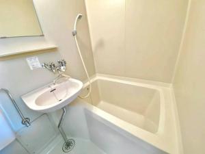 a white bathroom with a sink and a bath tub at LemonRooms in Aomori