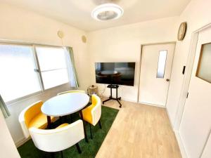 a living room with a table and chairs and a tv at LemonRooms in Aomori