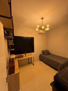 a living room with a bed and a large screen television at Casa Belchior in Sobral