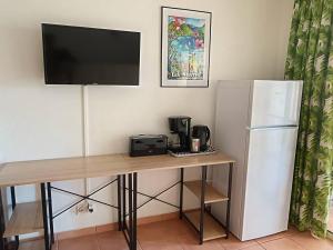 a desk with a television and a refrigerator at Le Tropical in Sainte-Anne
