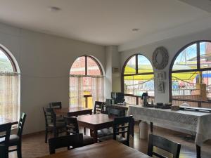 a dining room with tables and chairs and windows at Juan Placido Hospedaje in Cusco