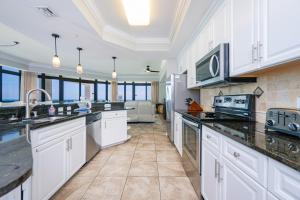 a kitchen with white cabinets and black counter tops at The Oasis 411 formerly Phoenix West II 411 in Orange Beach