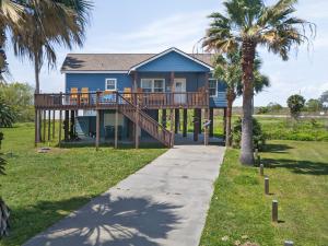 a house with a large deck and palm trees at Caribbean Palm Retreat 3BR Near Crystal Beach Fireplace in Bolivar Peninsula