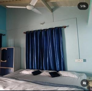 a bed in a room with a blue curtain at Harender nayal homestay in Bhīm Tāl