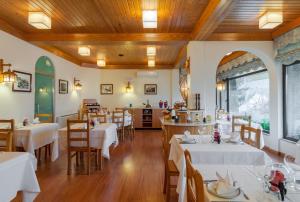 um restaurante com mesas e cadeiras brancas e tectos em madeira em Hotel Berne em Manteigas