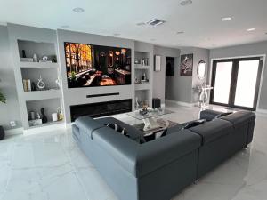 a living room with a black couch and a tv at Fun n Chic house with pool in Miami in Golden Glades