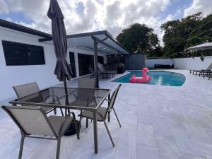 a patio with a glass table and a pink swan in a pool at Fun n Chic house with pool in Miami in Golden Glades