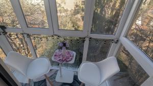 two white chairs and a table in a room with windows at Edmay Byrelax in Sighetu Marmaţiei
