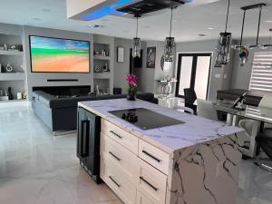 a kitchen and living room with a tv on the wall at Fun n Chic house with pool in Miami in Golden Glades