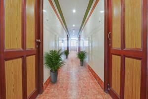 a hallway with two potted plants in a building at Hotel O Sasti Inn in Pondicherry