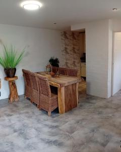 a dining room with a wooden table and wicker chairs at Thuis op Flakkee in Ooltgensplaat
