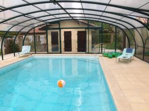 an indoor swimming pool with a glass house with a ball in it at Sans Souci Gite in Cahuzac