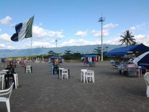 a beach with white chairs and blue umbrellas and a flag at Suítes Córdoba SP in Bertioga +48 photos