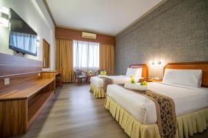 a hotel room with two beds and a desk at Hotel Sandakan in Sandakan