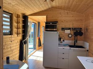 a kitchen with a white refrigerator in a wooden room at La Tiny du Clos Ernest in Cheminot