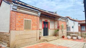a brick house with a red door on a street at 隆馨大悅古厝旅宿 in Jinhu