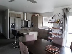 a kitchen with a wooden table and a dining room at Cosy Mangawhai House in Mangawhai