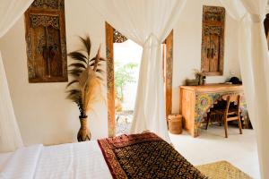 a bedroom with a bed and a table and a window at Romantic private villas Buvillas nusa penida in Nusa Penida