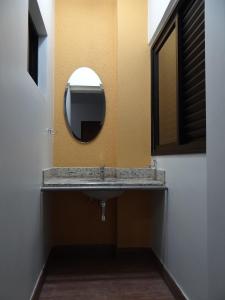 a bathroom with a sink and a mirror at Paradise Hotel in Campo Grande