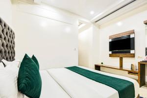 a bedroom with a bed and a flat screen tv at Hotel Saffron Inn in New Delhi