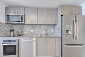 a kitchen with stainless steel appliances and wooden cabinets at Modern Studio Pool View Downtown Doral' Heart in Miami
