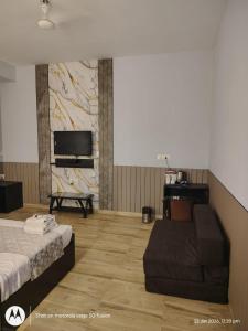 a room with a bed and a couch and a tv at Krishna Kunj Resort in Chhatikara