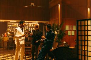 three men standing in a bar looking at their cell phones at Governor's Residence in Yangon +64 photos