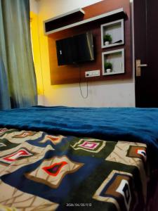 a bedroom with a bed with a blue blanket and a tv at Bloom Hotel in Jagādhri