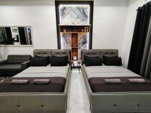 zwei Betten in einem Zimmer mit einer Couch in der Unterkunft Mini Concept Hotel in Kuala Terengganu