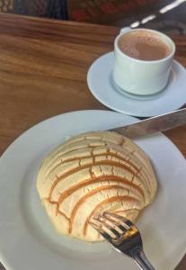 a pastry on a plate with a fork and a cup of coffee at Un poco de paz in Puebla