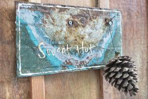 a rusty sign on a wooden wall with a pine cone at Little hut in Kampong Kundassan