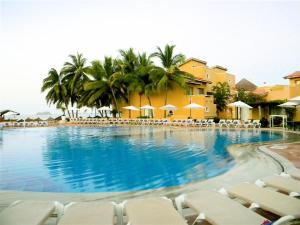 a large swimming pool with chairs and umbrellas at ENNA INN IXTAPA DEPARTAMENTO 01 RECAMARA ViSTA MAR in Ixtapa