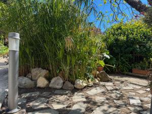 a pole in a garden with rocks and plants at Fortuna Garden House in Imperia