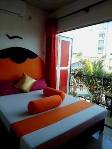 a bedroom with a bed with an orange headboard and a window at Thambili lk in Colombo