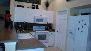 eine Küche mit weißen Schränken und einem weißen Kühlschrank in der Unterkunft Villa Andromeda in Cape Coral
