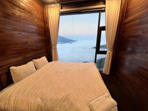 a bedroom with a bed and a large window at Trúc house in Kon Rung (1)