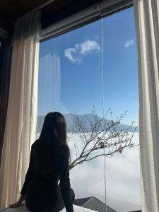 a woman sitting in a window looking out at Trúc house in Kon Rung (1)