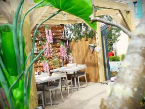 a patio with tables and chairs and a fence with flowers at Chez Laurence in Locronan