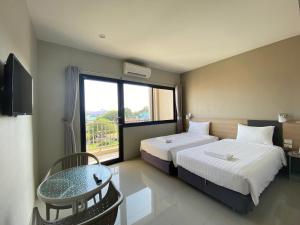 a bedroom with two beds and a table and a window at Prachuap Beach Hotel in Prachuap Khiri Khan