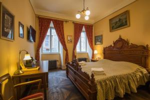 a bedroom with a bed and a desk and windows at Hotel Edward Kelly in Český Krumlov