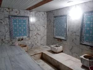 a bathroom with a tub and a sink and two windows at Hotel Cems Sunparadise in Alanya
