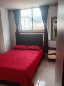 a bedroom with a red bed and a window at Edificio Karu in Pamplona
