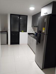 a kitchen with a black refrigerator and a white tile floor at Edificio Karu in Pamplona