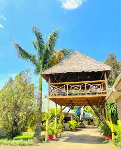 a building with a straw roof and a palm tree at Pakihotels&apartment in Moshi