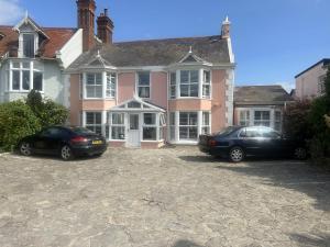 two cars parked in front of a pink house at Potters Mooring Guest House in Teignmouth