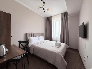 a bedroom with a bed and a desk and a television at Orion Hotel in Almaty